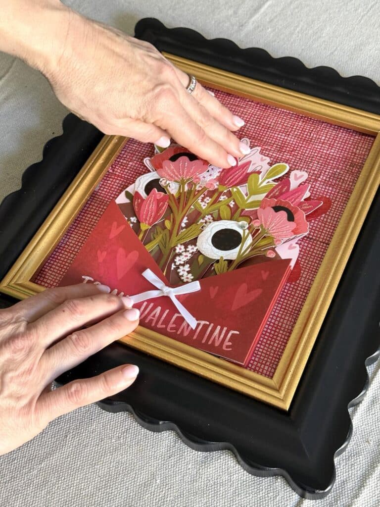 Gluing a 3-D valentine into a photoframe as heart-themed art.