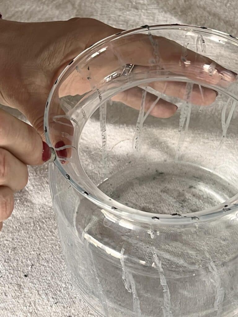 Drawing crayon lines on the lip of a vase for a crackled glass effect.