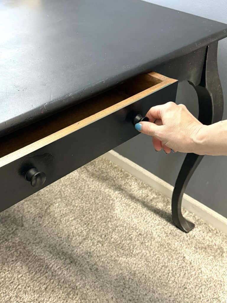 Pulling out the drawer of a bedroom desk.