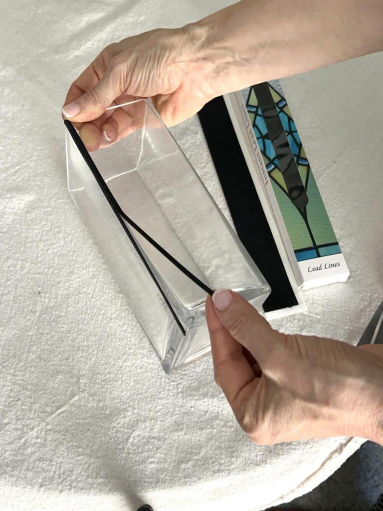 Applying a black lead line to the edge of a glass vase.