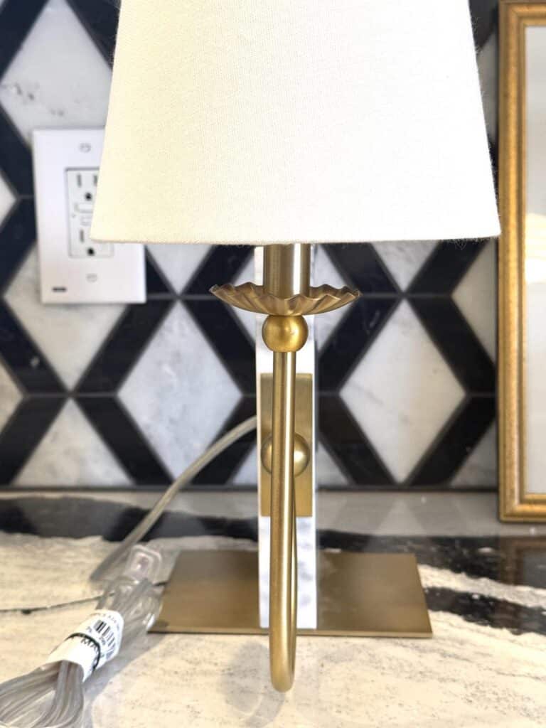 A brass lamp with a white shade sitting on kitchen counter.