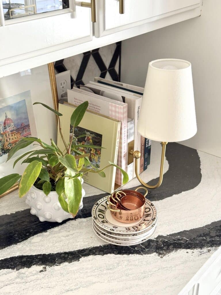 kitchen counter lamp ideas include styling this brass lamp with cookbooks and a plant.