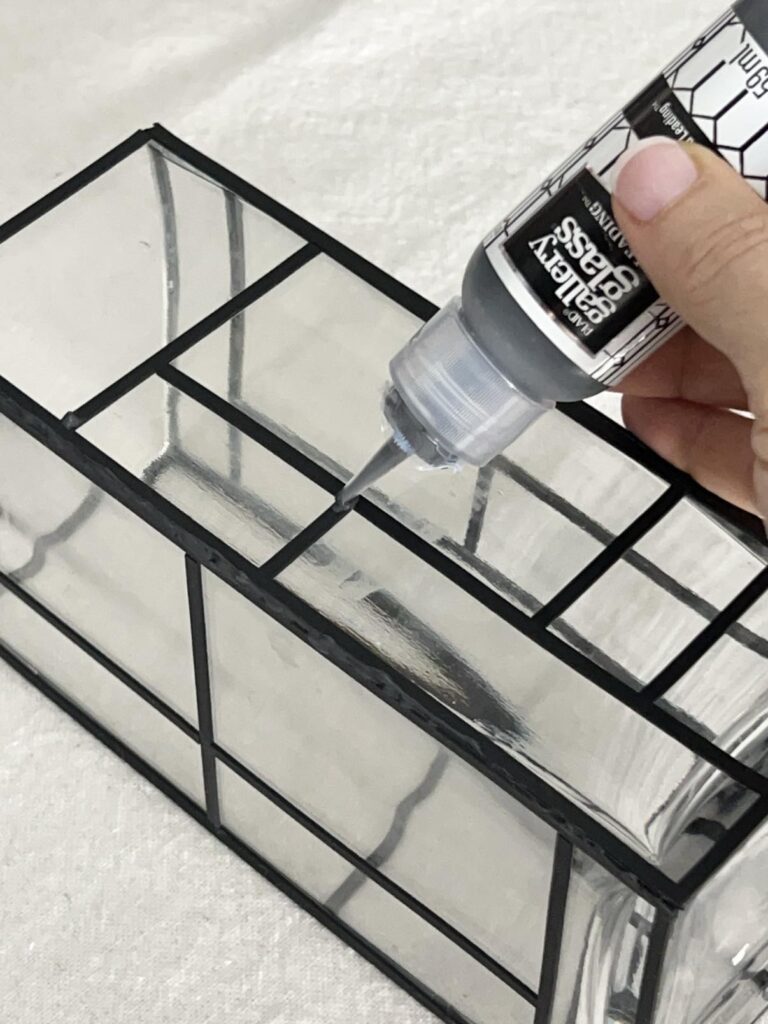 Applying liquid lead to stained glass painted vase.