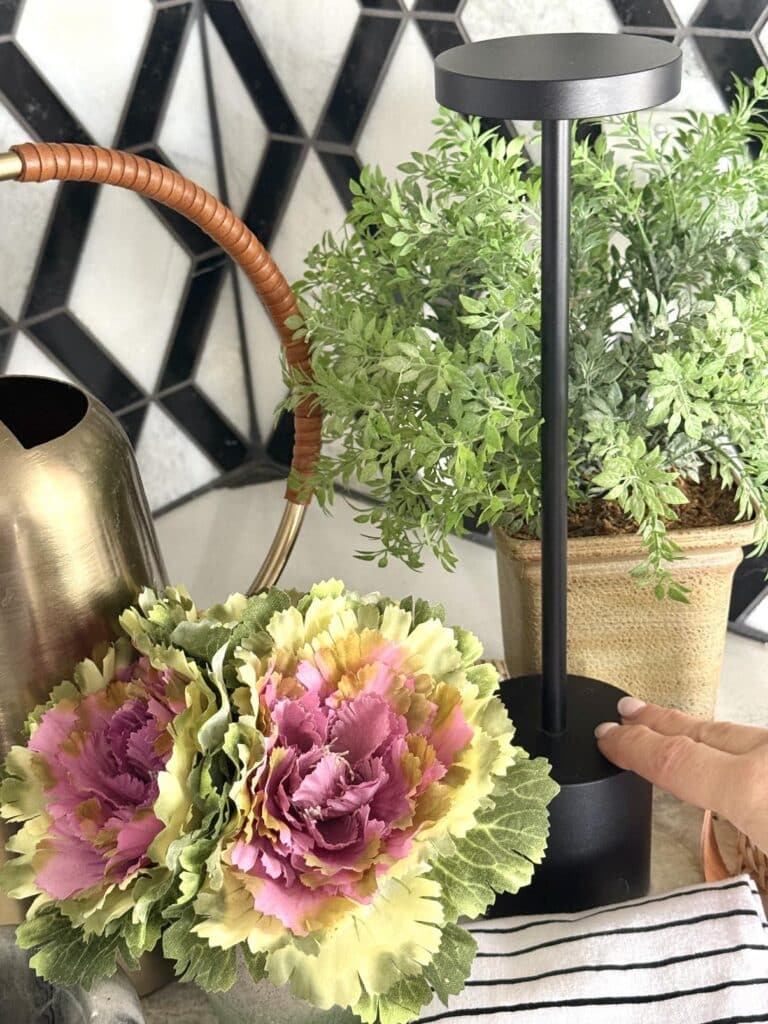 Woman's hand turning on a black stick wireless kitchen lamp on a countertop.