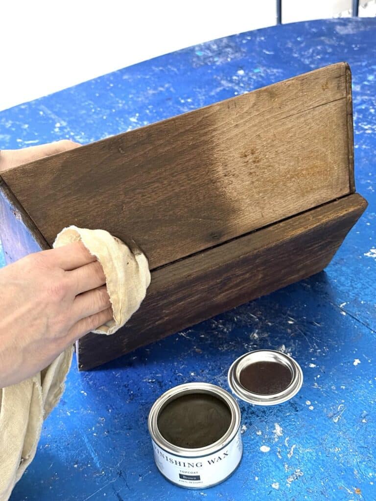 Rubbing finishing wax to outside of diy wood box centerpiece.