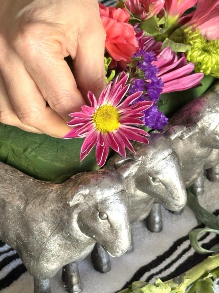 Placing a purple daisy into florist foam.