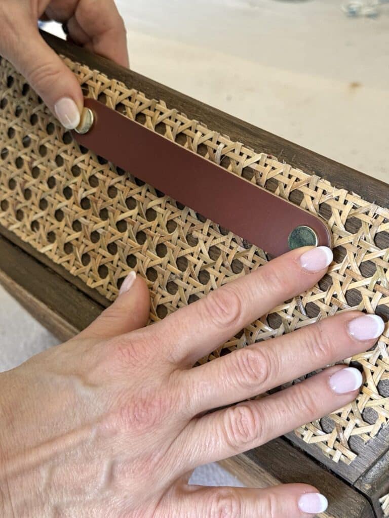 Pressing a leather drawer pull to the side of a diy wood box centerpiece.