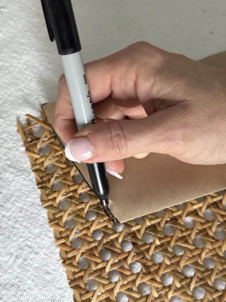 Tracing a pattern onto a sheet of rattan.