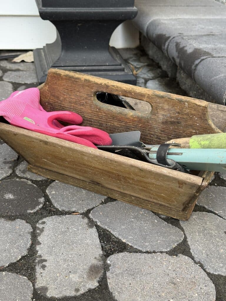 A wooden box filled with garden tools.